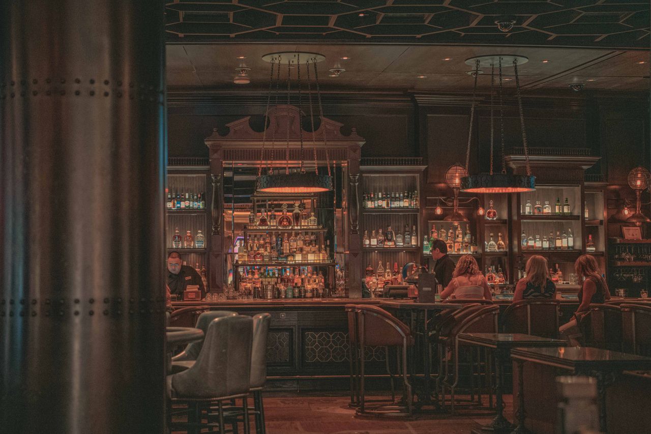 Warm and inviting bar scene with patrons enjoying drinks amidst vintage decor and ambient lighting.