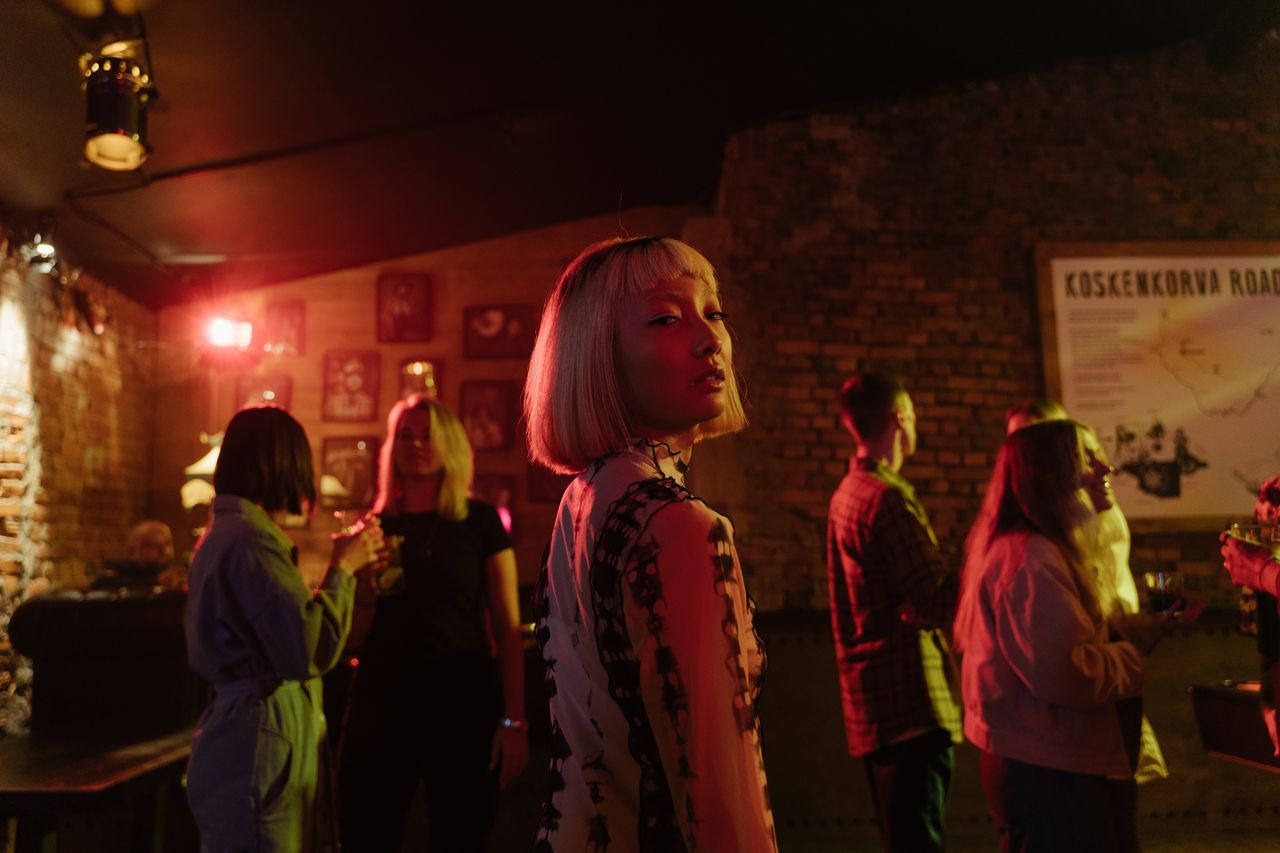Group of stylish adults enjoying a vibrant night out in a trendy bar setting.